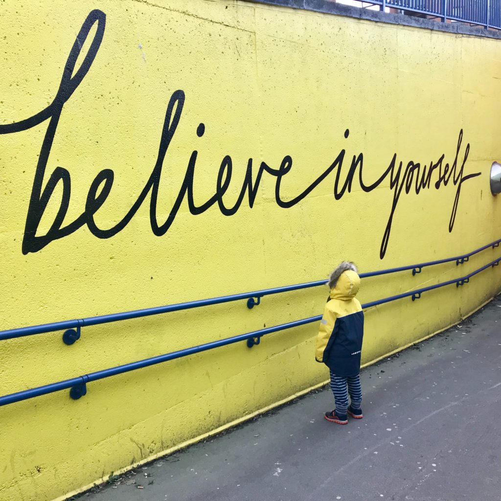 An image with a positive affirmation painted on a yellow wall